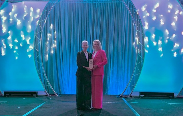 Julee Briscoe Waldrop and Jayne Jennings Dunlap onstage at the 2025 Sigma Awards ceremony accepting the  Capstone International Nursing Book Award.